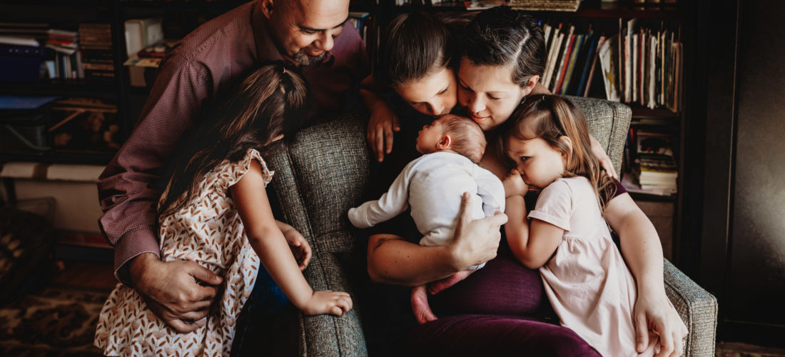 Family of 6 gathered around a their newborn baby during a San Diego in-home lifestyle newborn photo session by Love Michelle Photography.