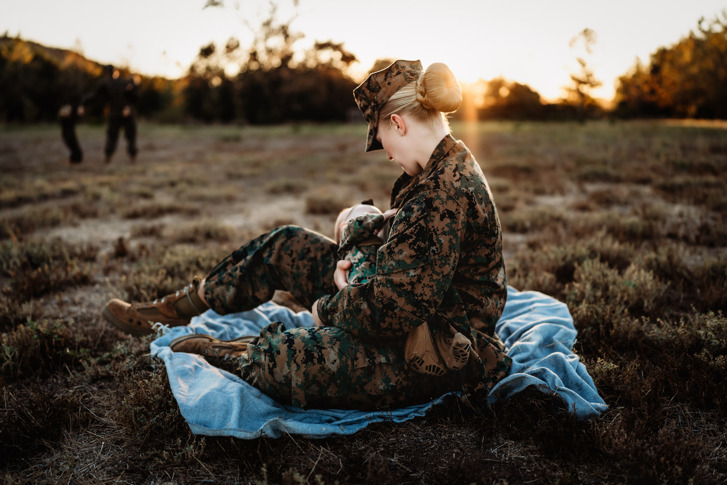 Marine Corp mom in uniform breastfeeding sitting in a field breastfeeding her baby during a military family photo session in San Diego
