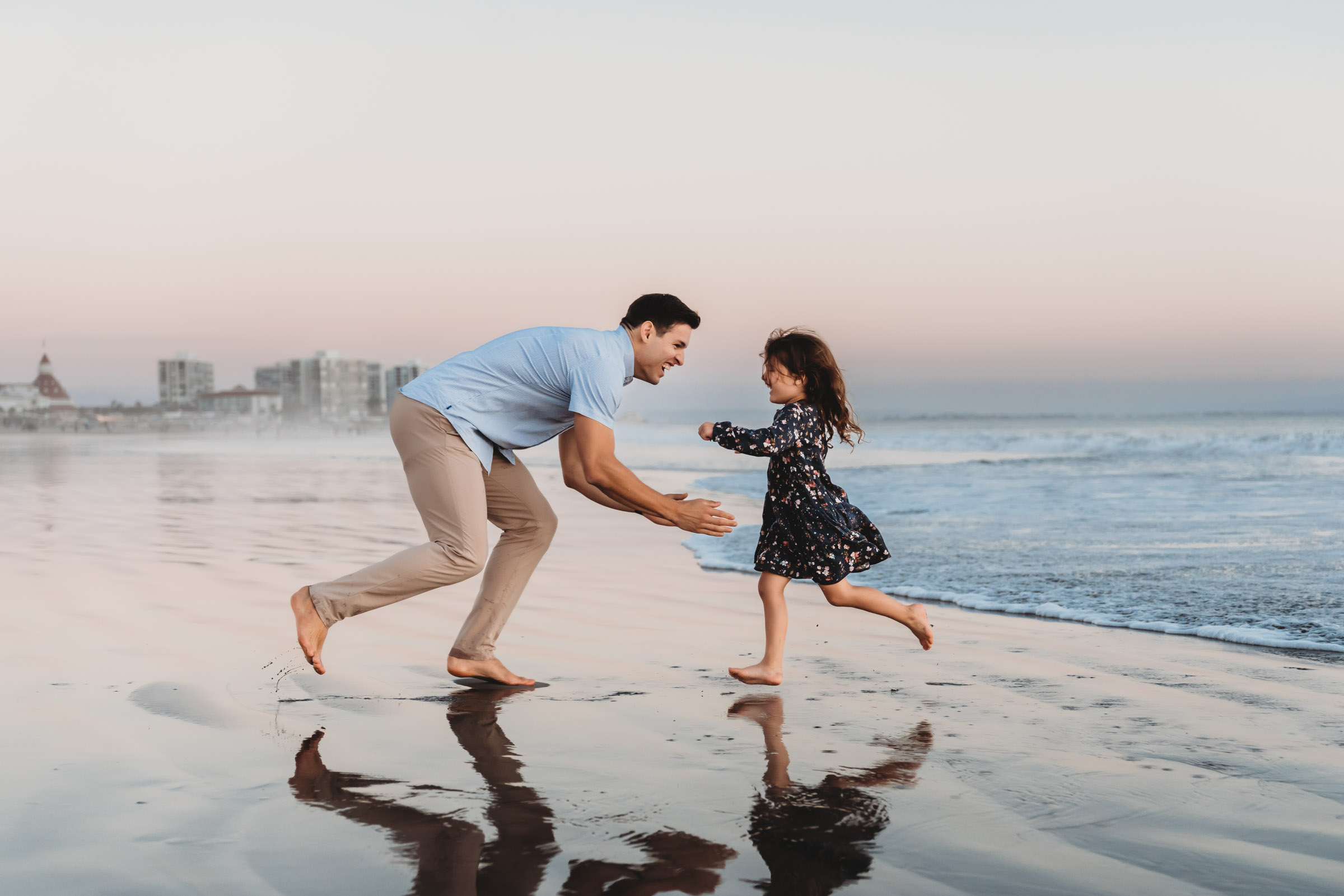 Daughter running into father's arms  during a lifestyle family photography session on Coronado Beach.