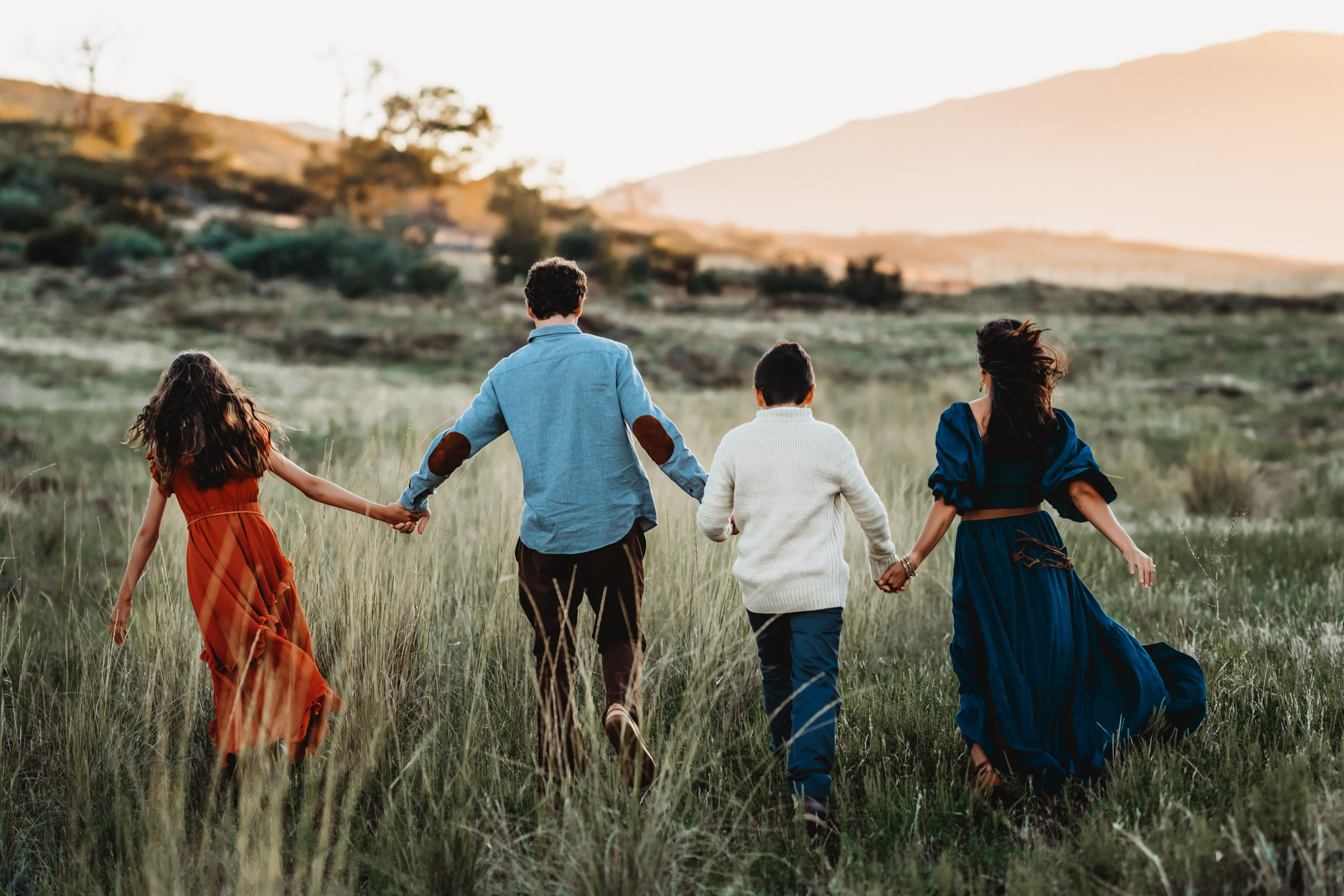 Family holding hands and walking away from camera during family photography session on Mt. Laguna. 