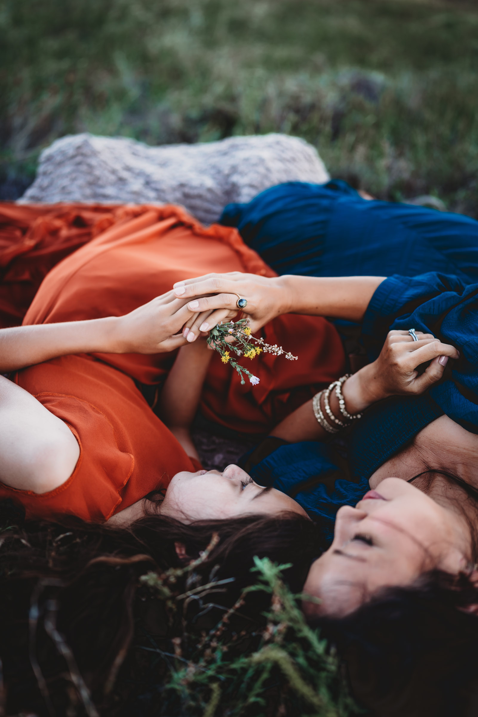 Mom and daughter laying down in a meadow holding flowers during a family photography session on Mt. Laguna. 