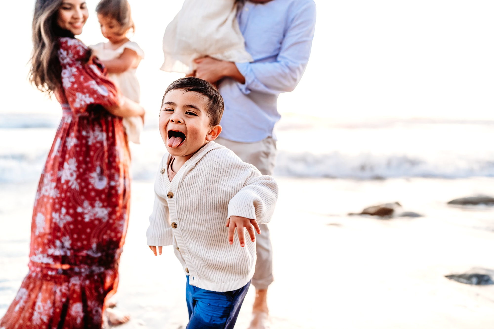 Little boy sticking his tongue out at the camera during a beach family photo session in Del Mar, California. 