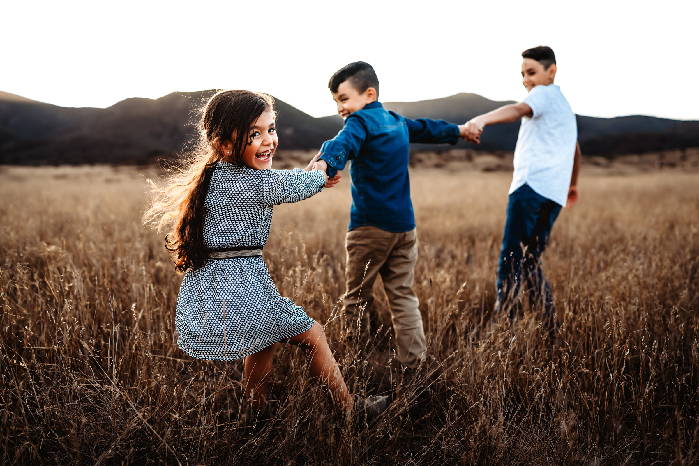 Little girl and brothers playing tug of war during a family photography session in Mission Trails Regional Park.