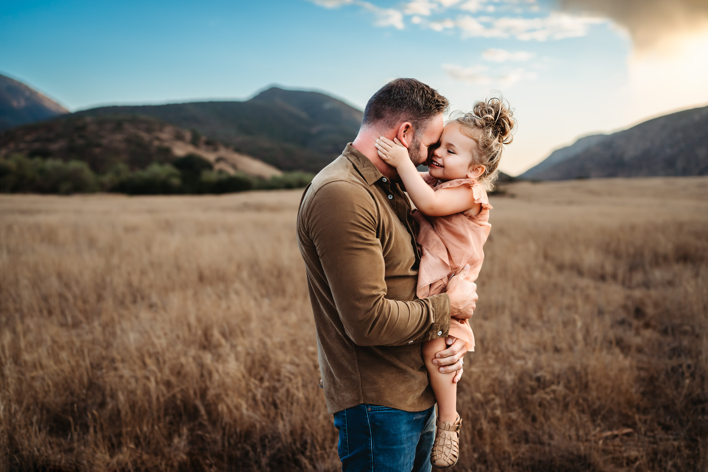 Dad and little girl hugging on a field during a lifestyle family photo session at Mission Trails Regional Park 