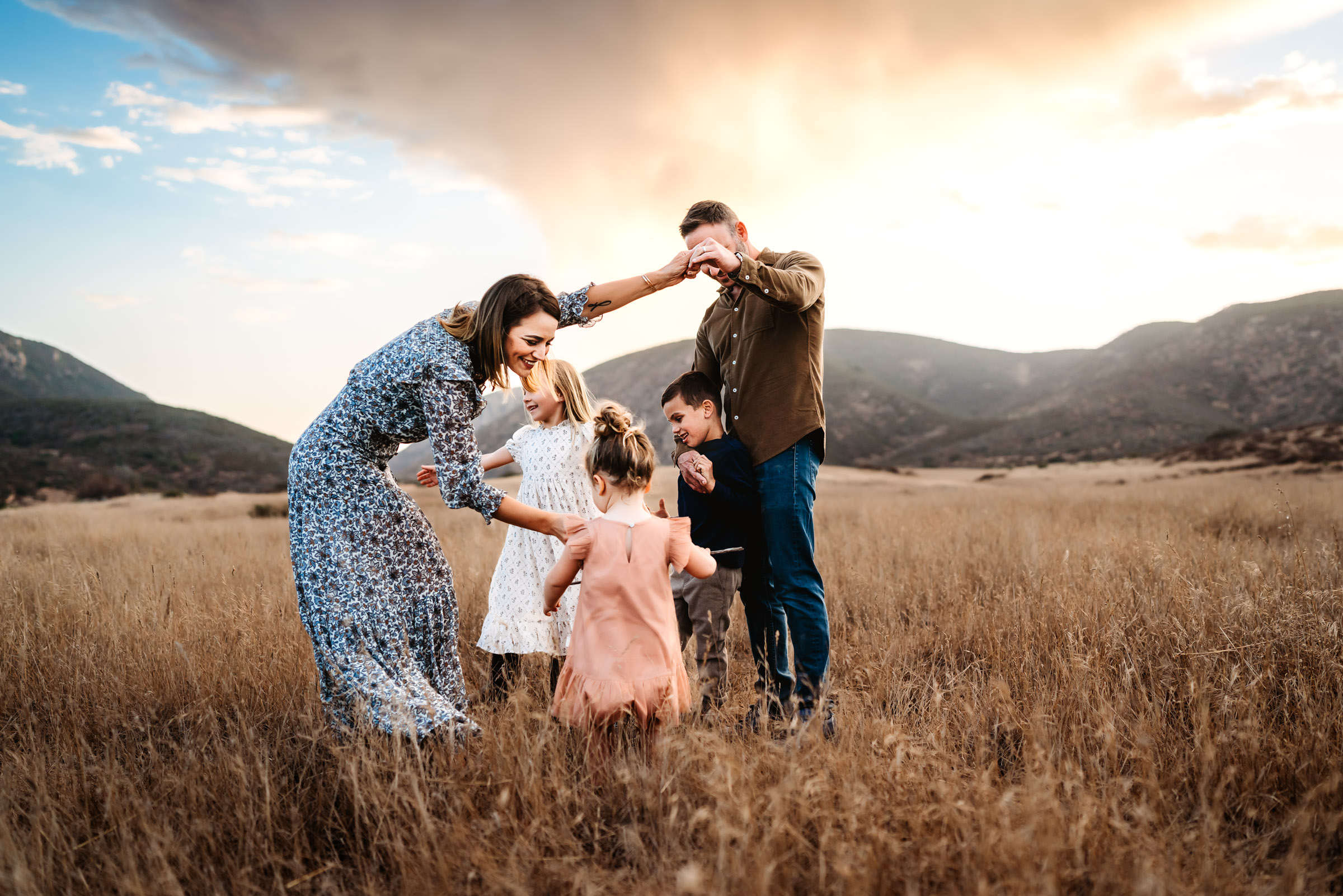 Mom and Dad holding hands with kids in a field during a family photography session in Mission Trails Regional Park 