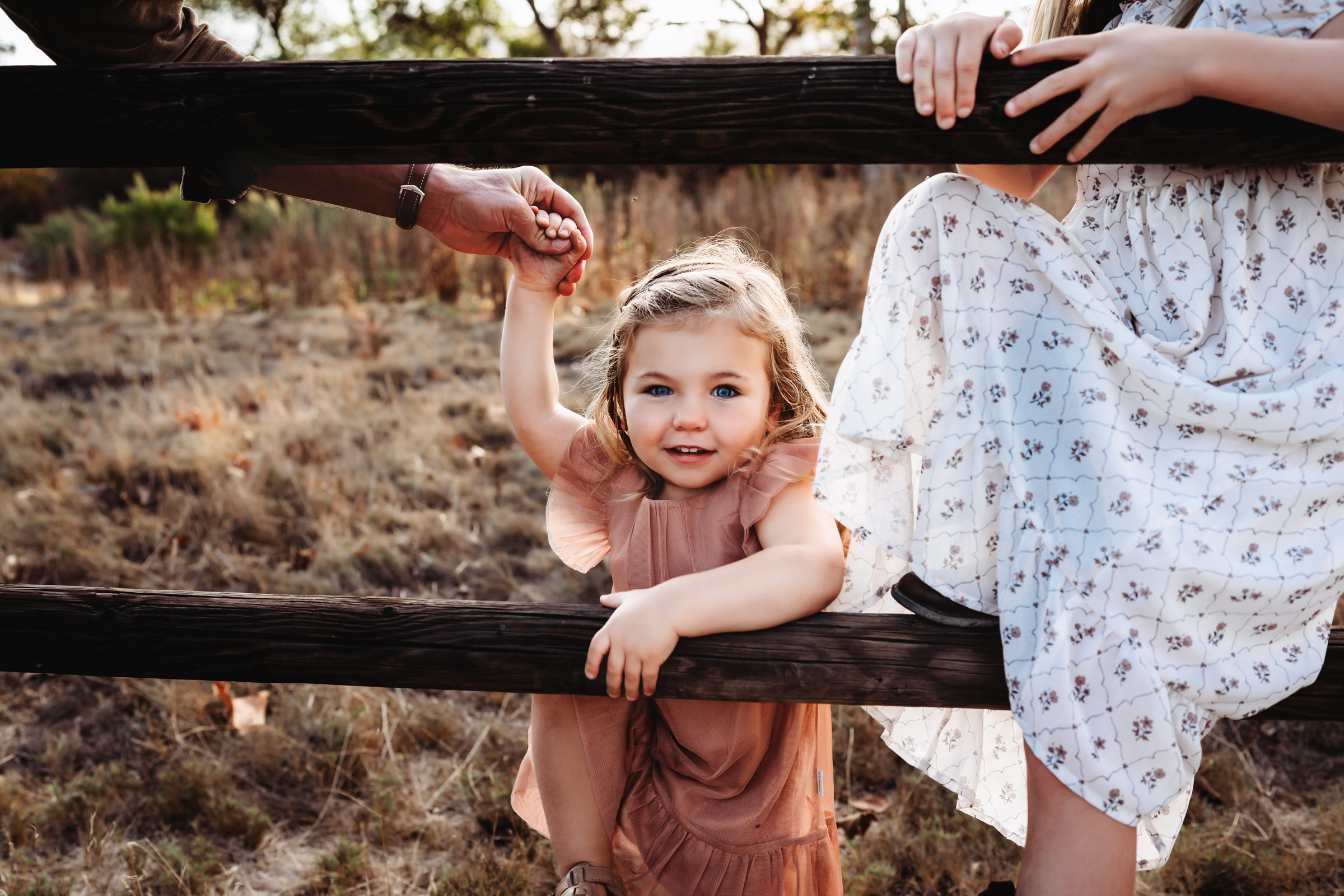 Little girl climbing a wooden fence during a lifestyle family photography session at Mission Trails Regional Park
