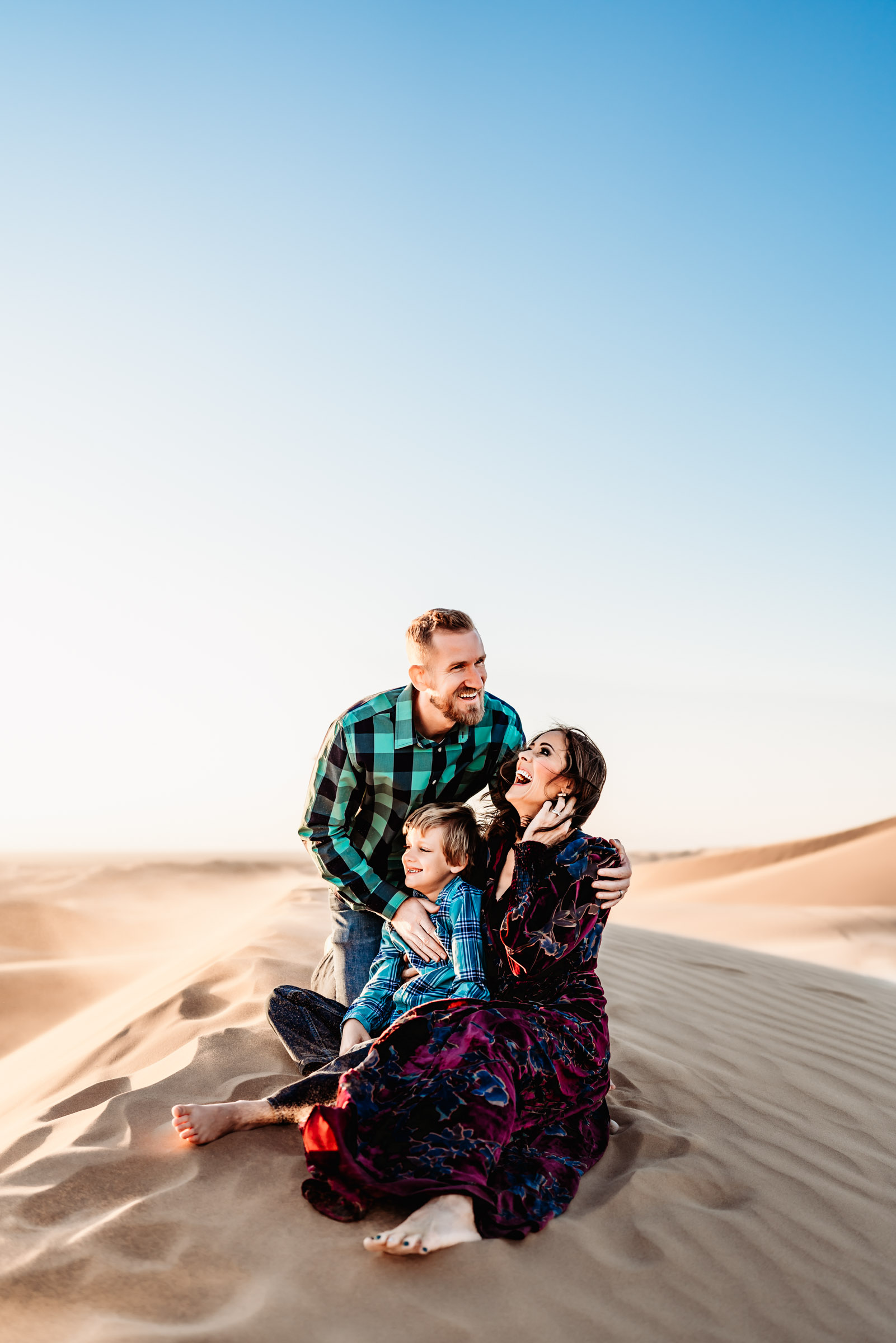 Family sitting on top of a sand dune on the Imperial Sand Dunes near Glamis during a San Diego lifestyle family photography session.