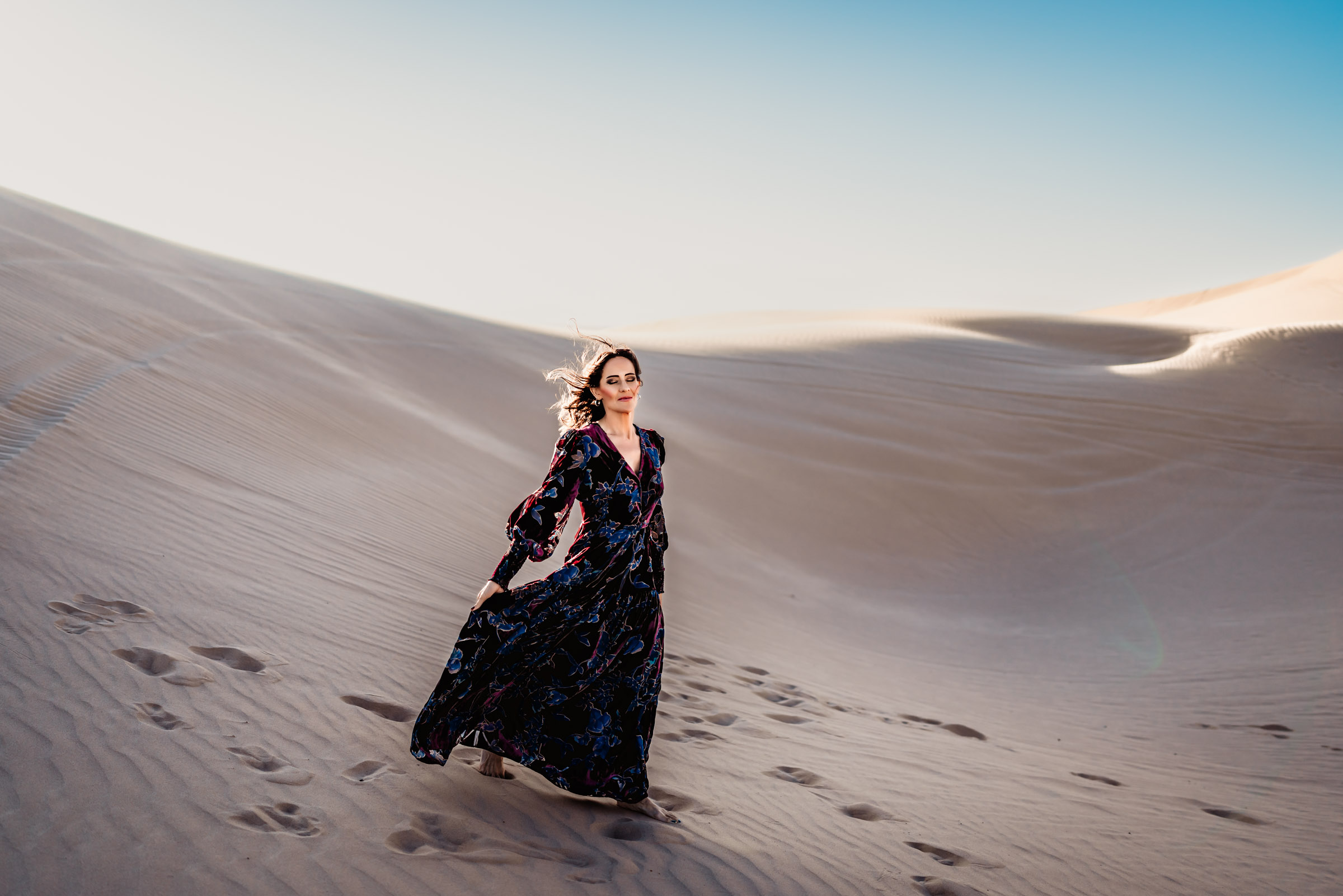 Woman holding dress walking on the Imperial Sand Dunes during a San Diego Lifestyle Photography Session