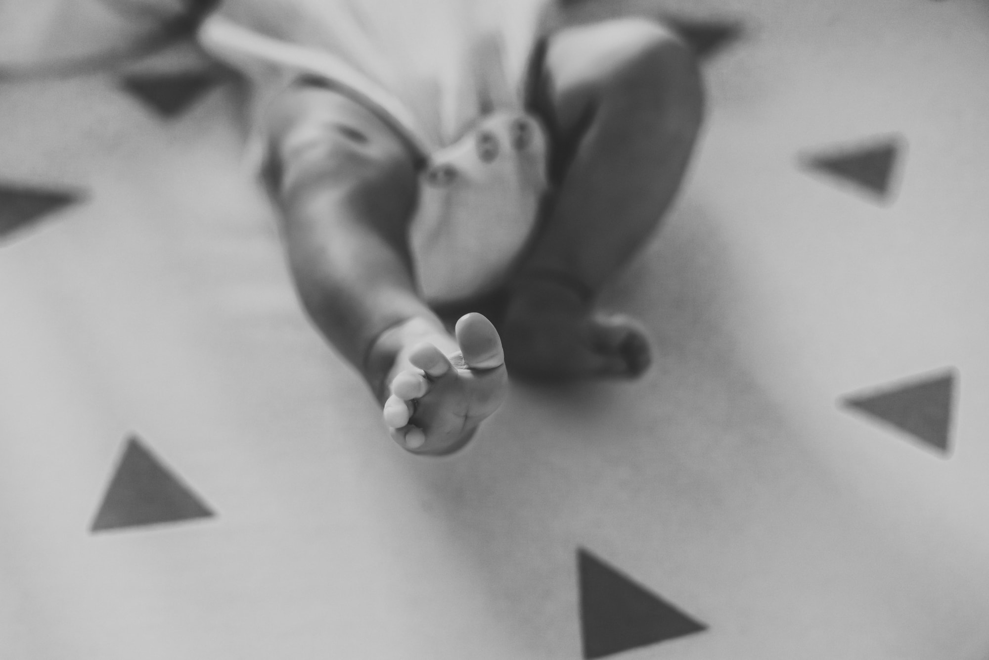 A newborn baby stretching out her foot toward the camera during a San Diego newborn photo session by Love Michelle Photography