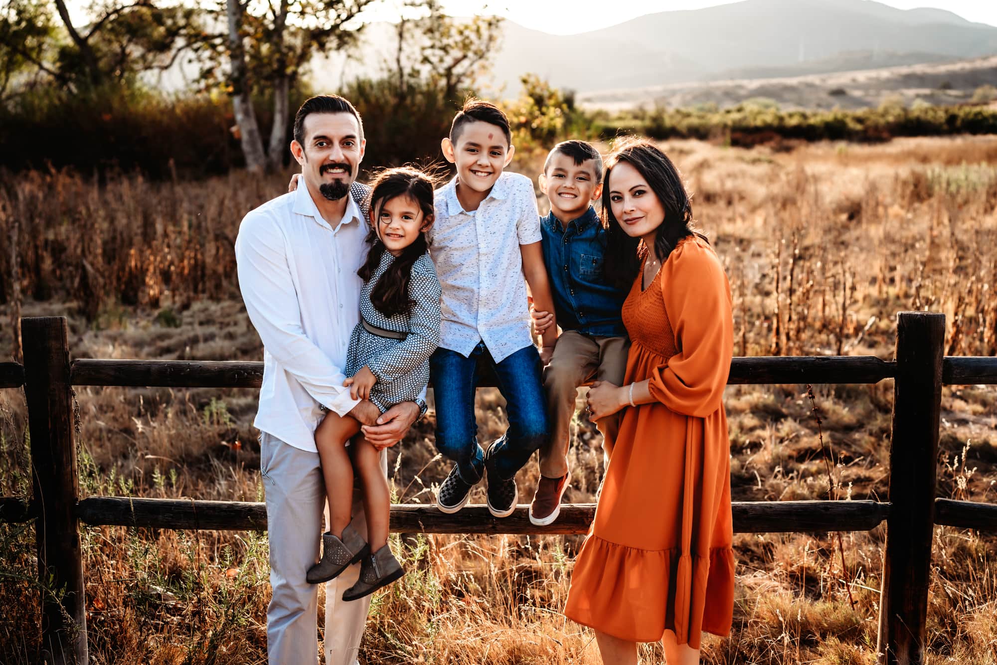 Family of five leaning against a fence in Mission Trails Regional Park during a family photo session in San Diego.