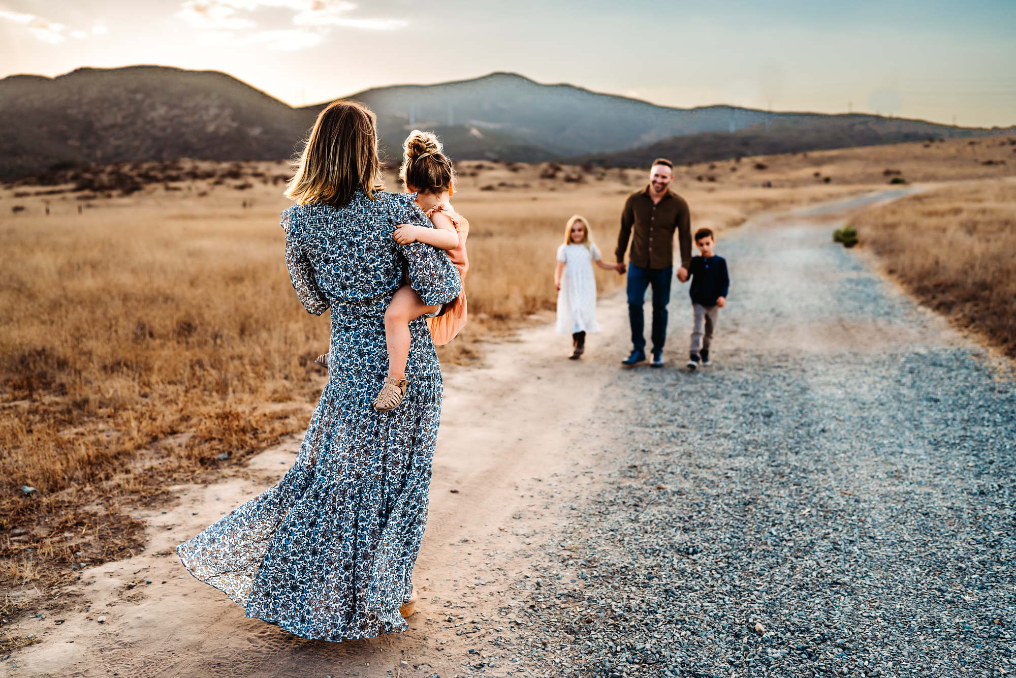 A family of 5 walking down a gravel road in Mission Trails Regional Park during a lifestyle family photography session by Love Michelle Photography. 