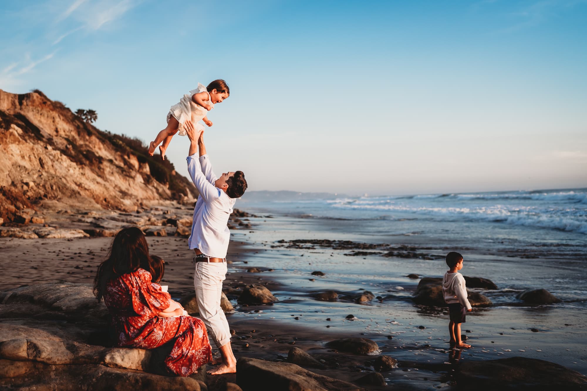 A family of five playing together on a beach in Del Mar, California during a lifestyle family photography session by Love Michelle Photography. 