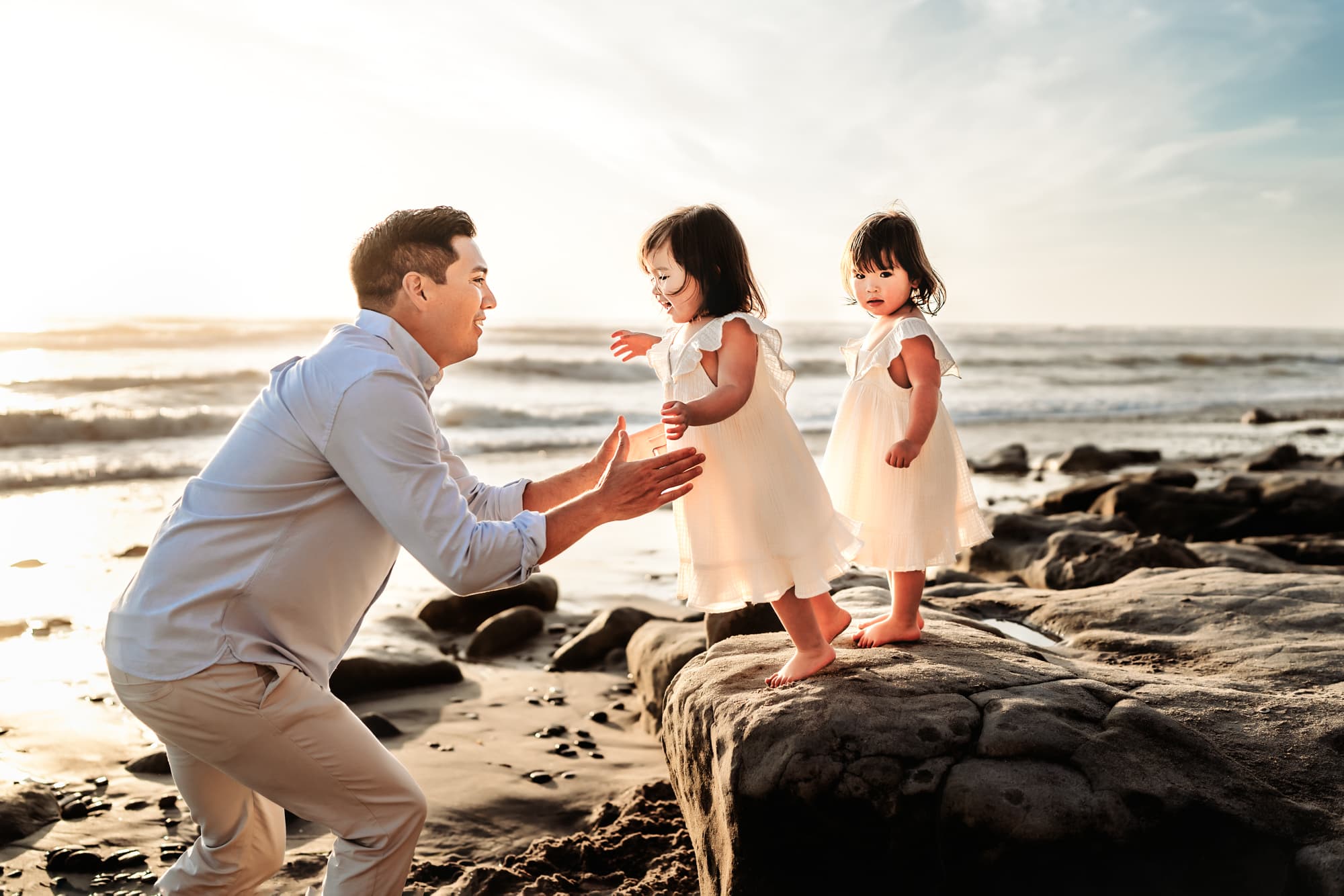A father playing with his twin daughters on a beach in Del Mar, California, during a lifestyle family photography session by Love Michelle Photography. 