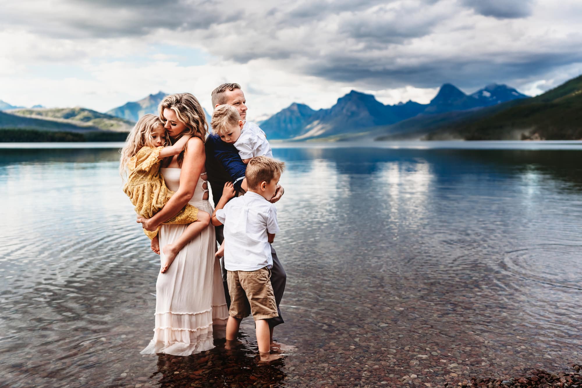 A family of 5 stands together on the shores of Glacier National Park's Lake McDonald during a Montana lifestyle family photography session by Love Michelle Photography.