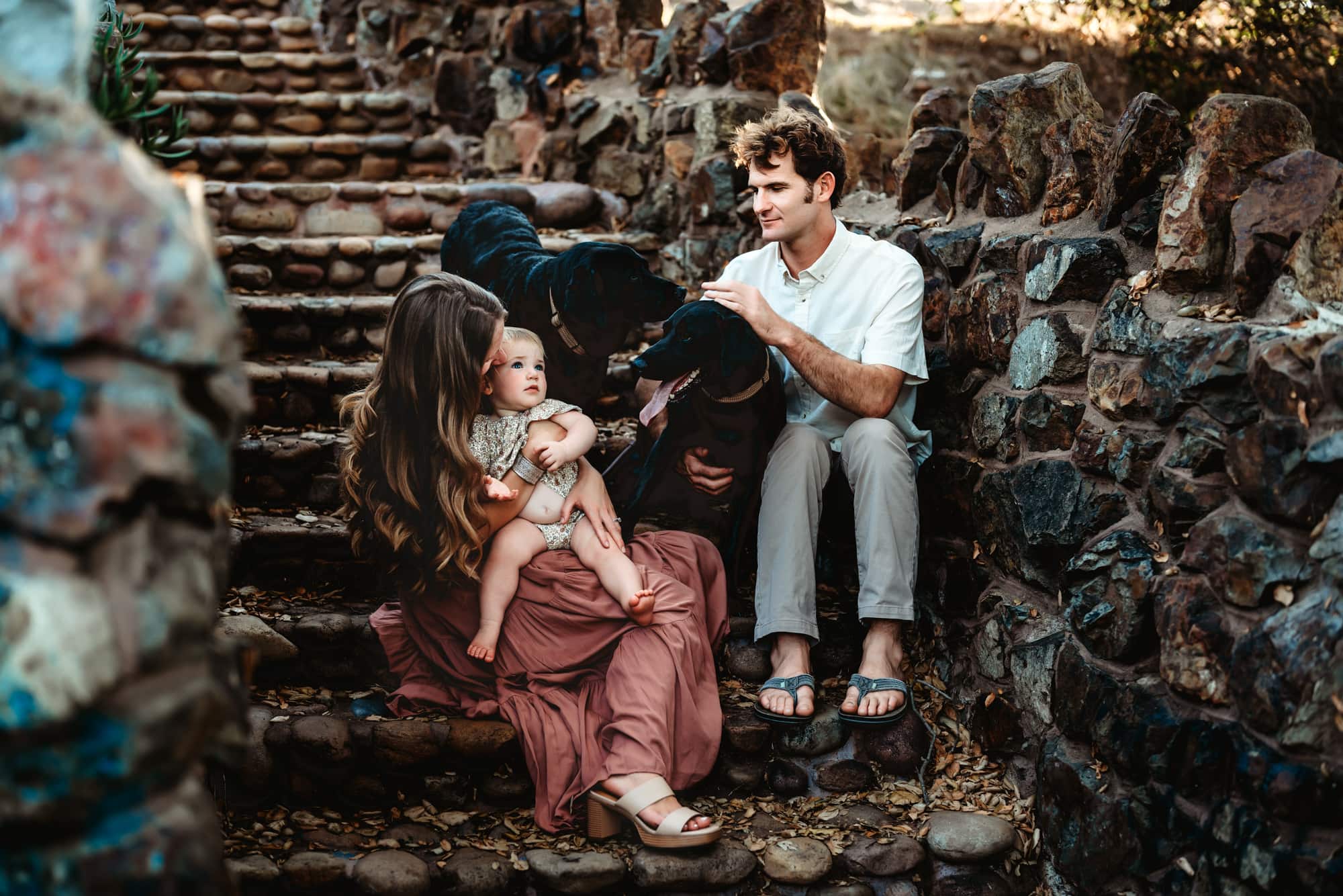 Young family sitting together on steps outdoors during family photos in San Diego