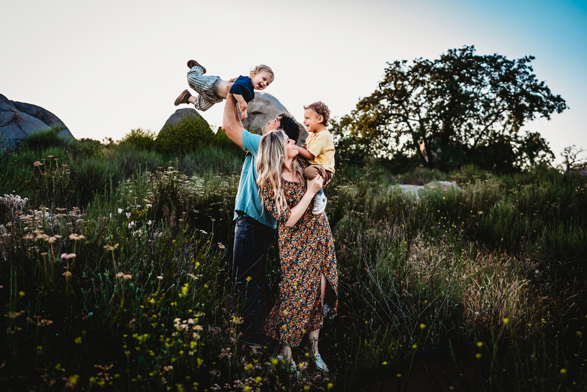 A family of four plays together in a field of wildflowers during a San Diego lifestyle family photography session by Love Michelle Photography. 