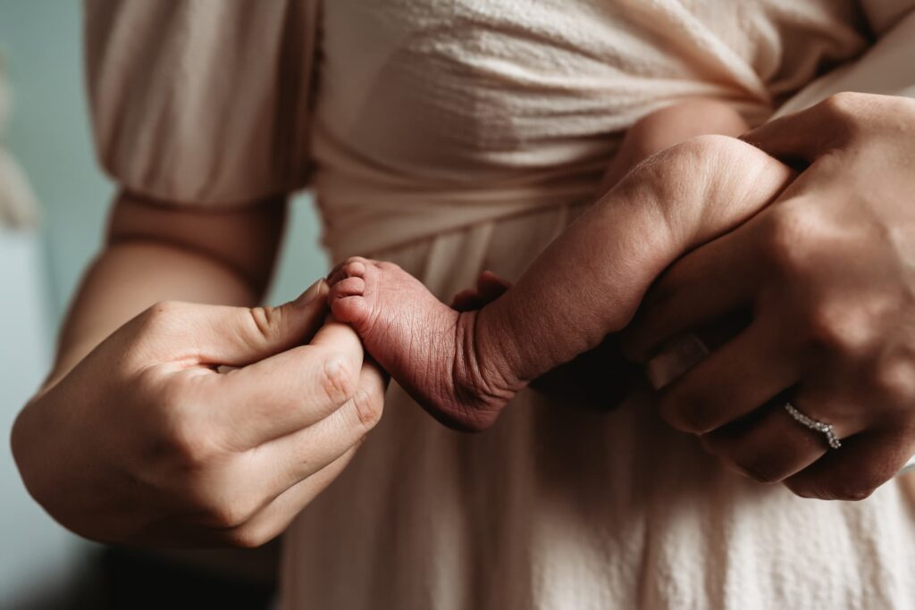 A new mom hold her newborn son's tiny, wrinkly foot.