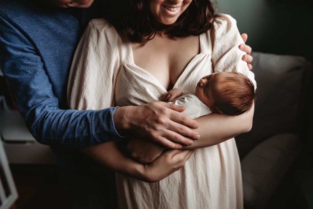 A new mom and dad hold and look at their baby boy. 