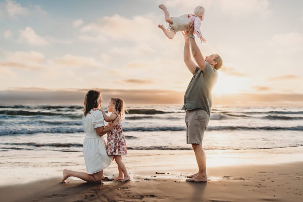 A family of four plays on Carlsbad State Beach during a family photoshoot. 