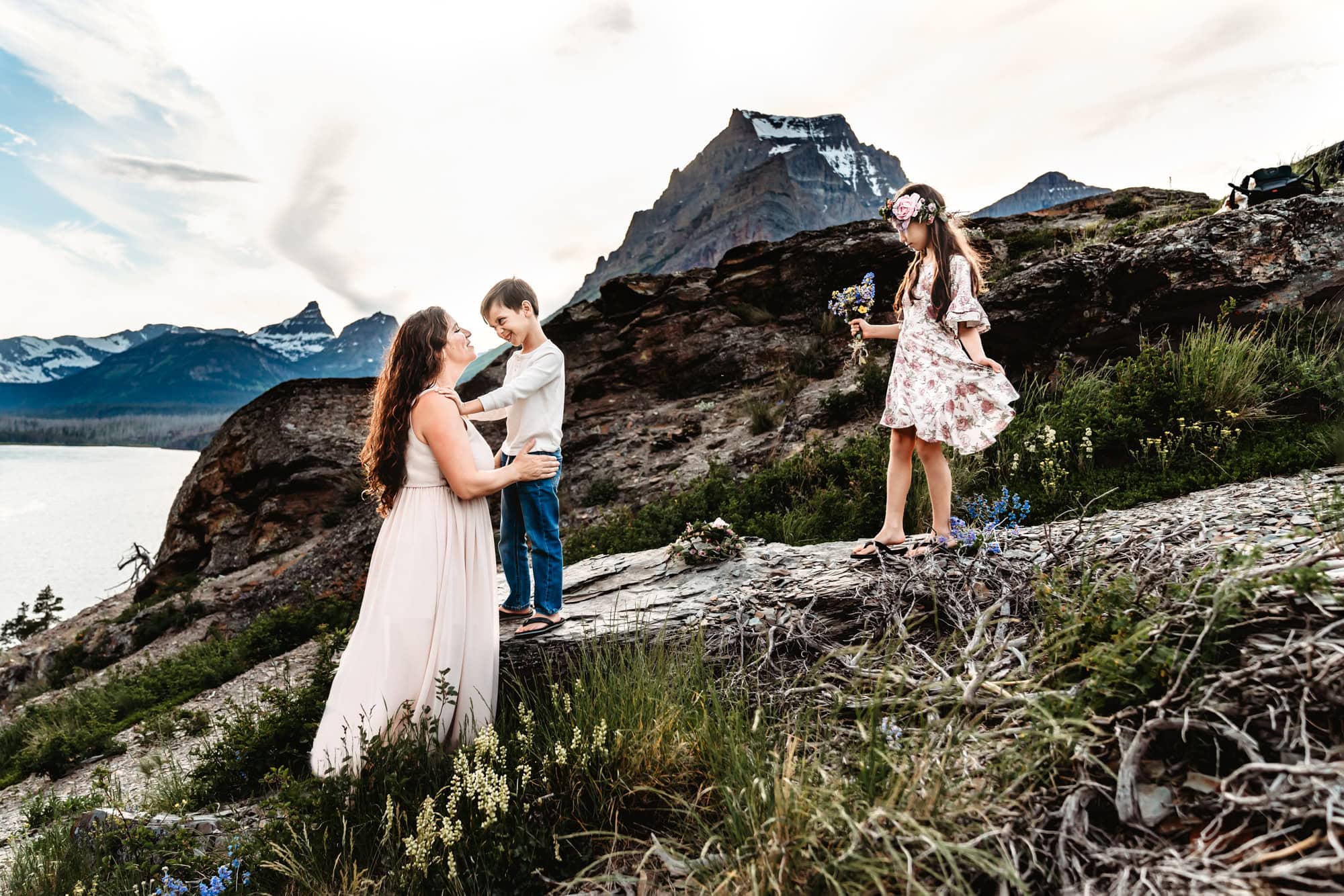 A mom plays with her two children on a boulder near St. Mary's Lake in Glacier National Park.