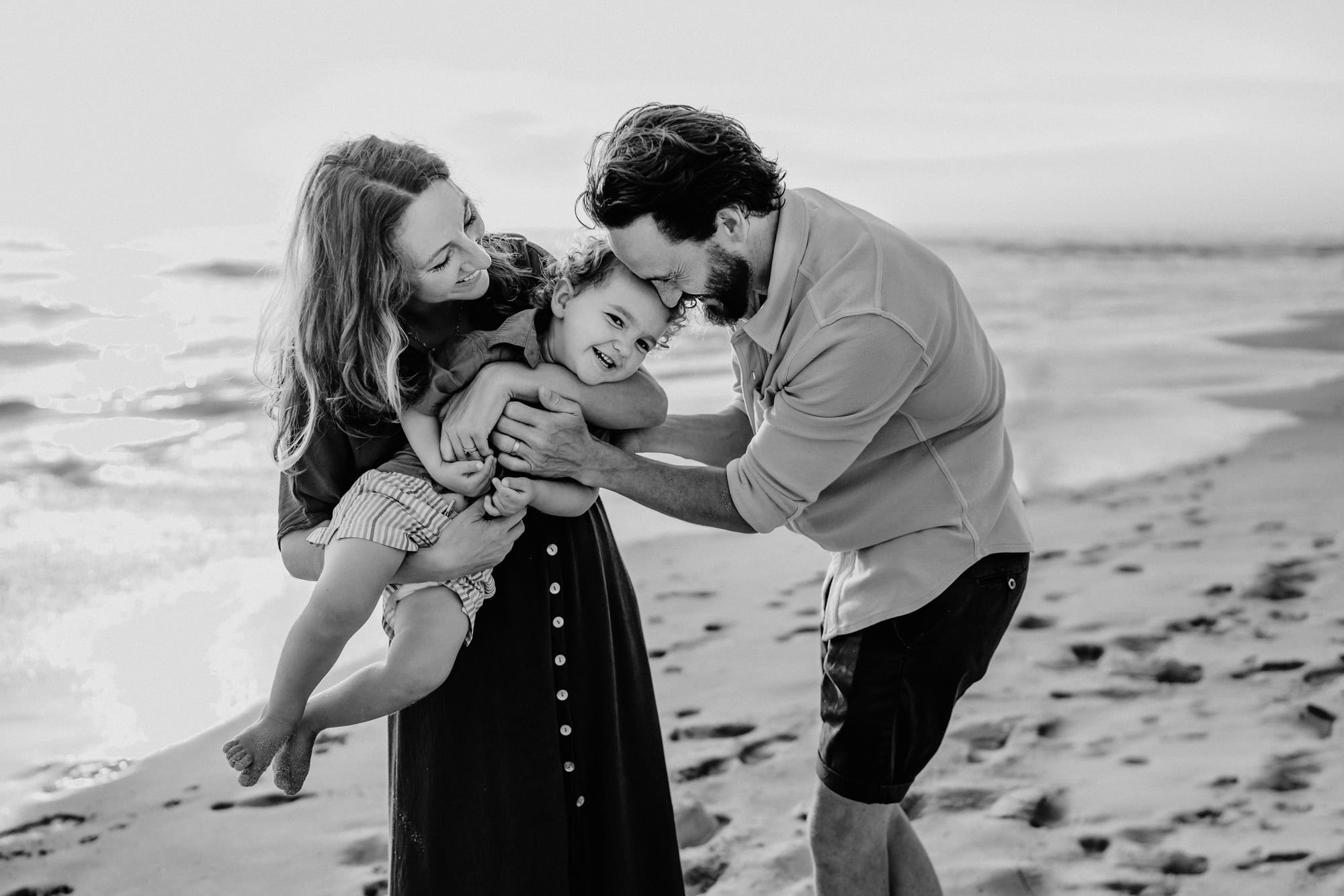 A man and woman play with their toddler son on La Jolla's Windansea Beach. 