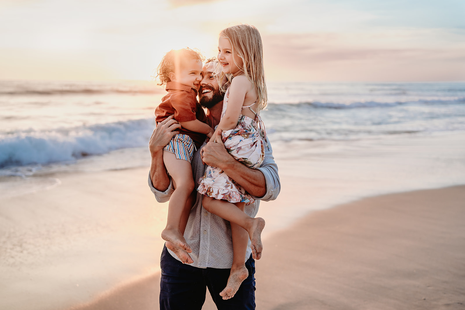 San Diego Family Photographer captures father holding children at golden hour on beach in San Diego