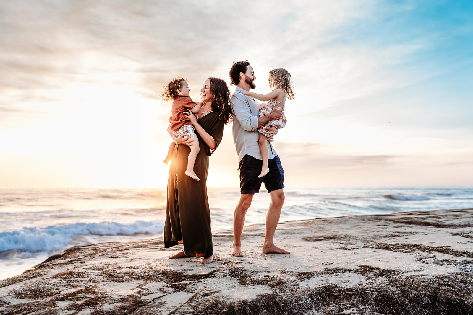 San Diego Family Photographer captures young family standing together on rocks during family beach photos in San Diego