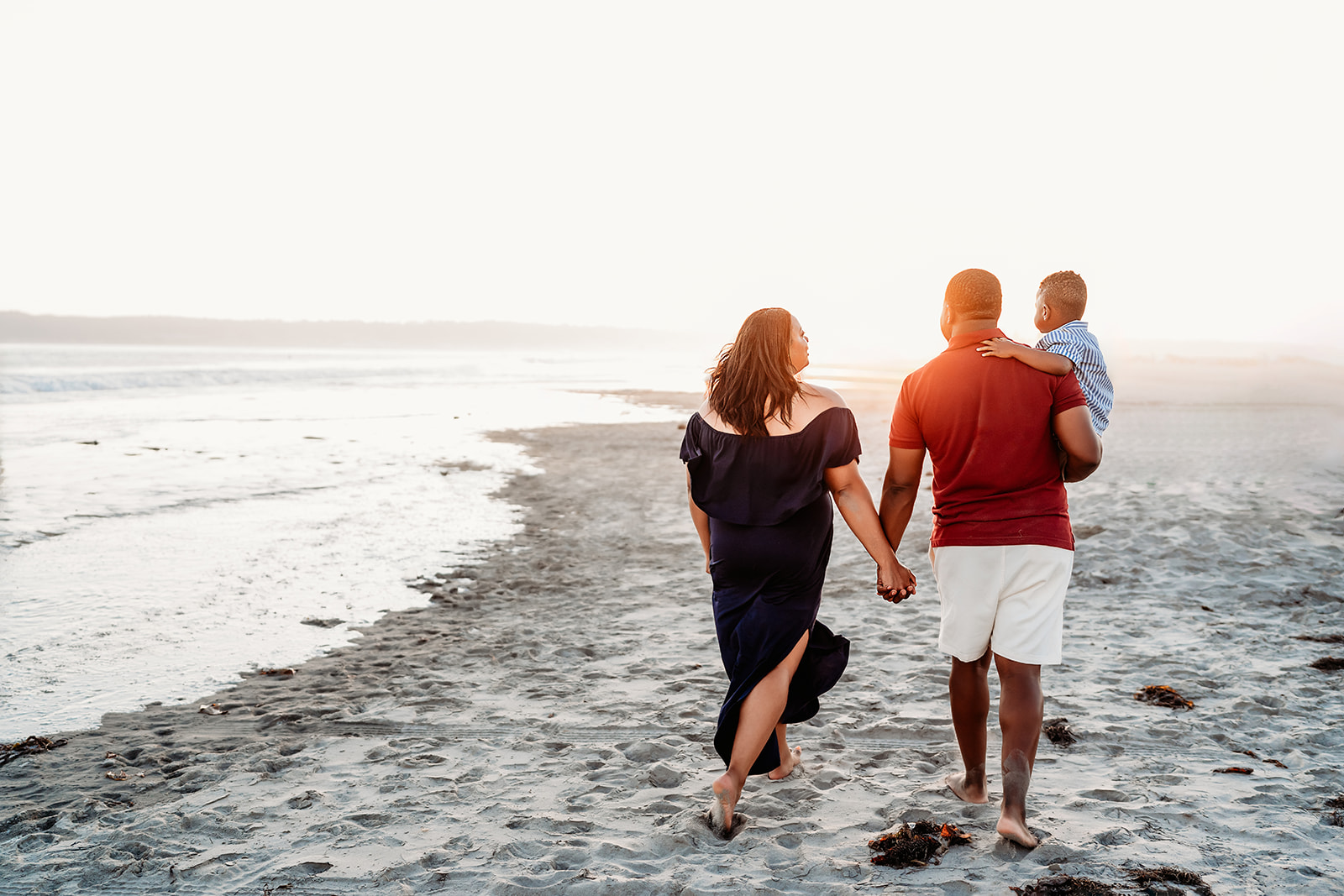 San Diego Family Photographer captures family walking on beach together into sunset