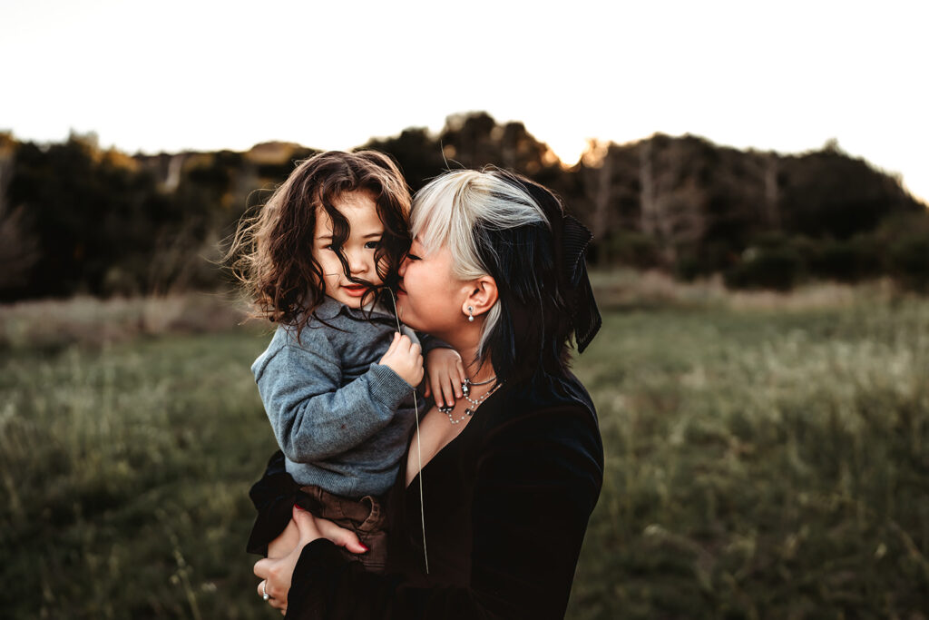 A mom snuggles her toddler son during an evening family photo session in San Diego. 