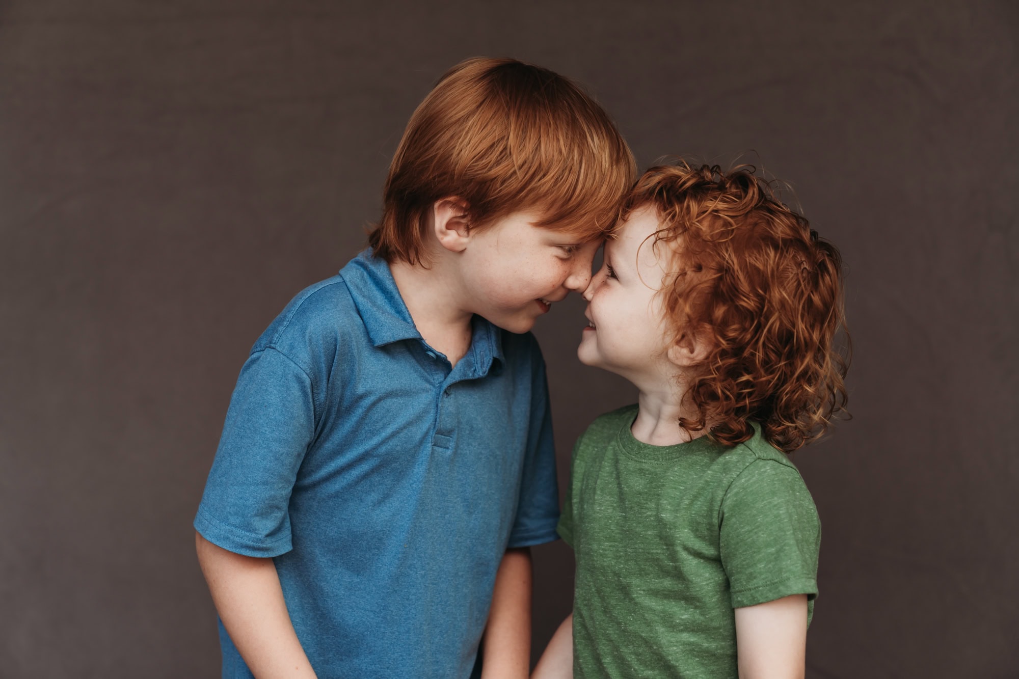 San Diego school photographer captures playful homeschool sibling portrait of two red-haired brothers touching noses and grinning.