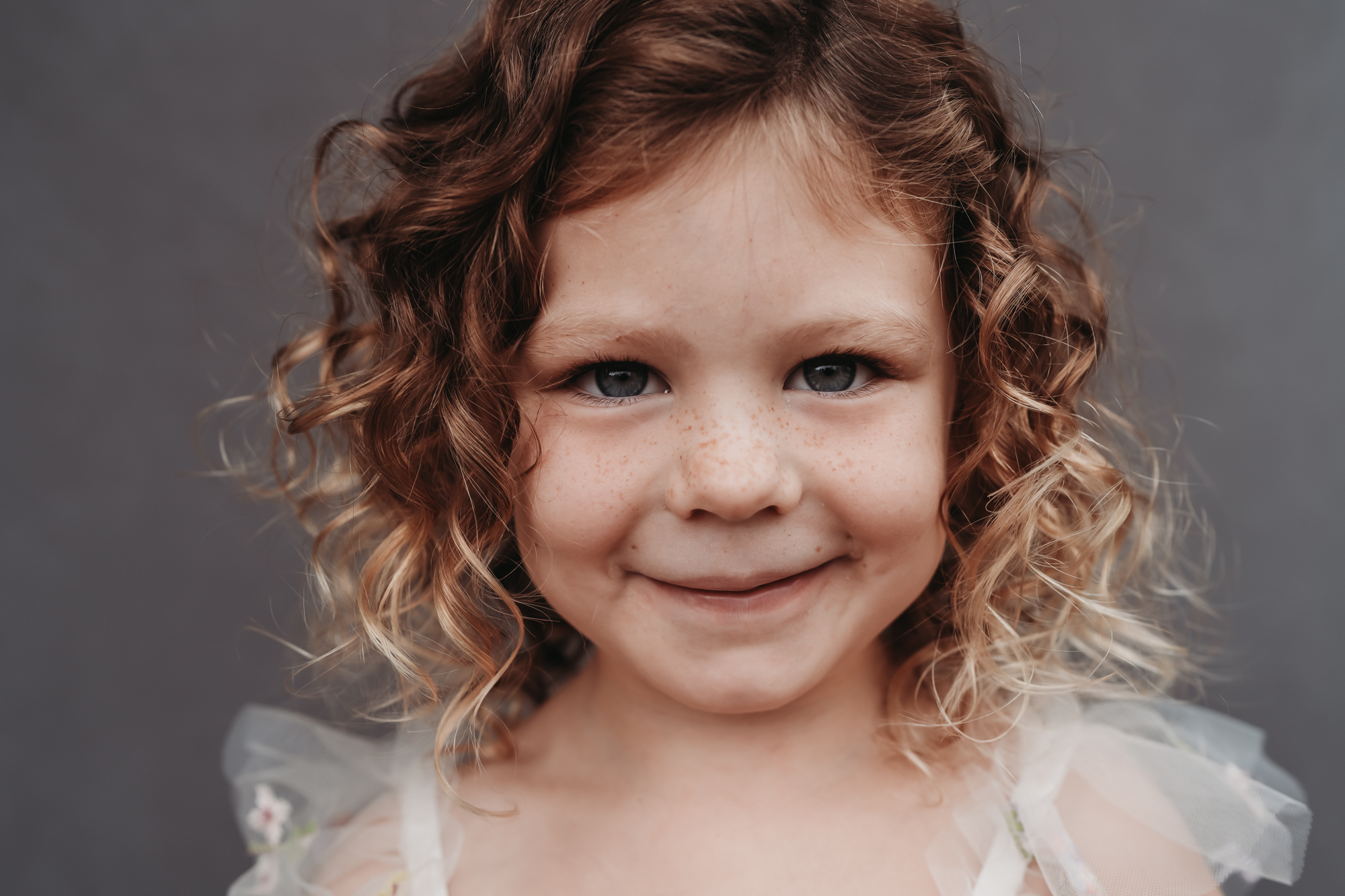 Close-up fine art preschool portrait of a curly-haired girl with soft natural light, demonstrating an example of fine art school photography.