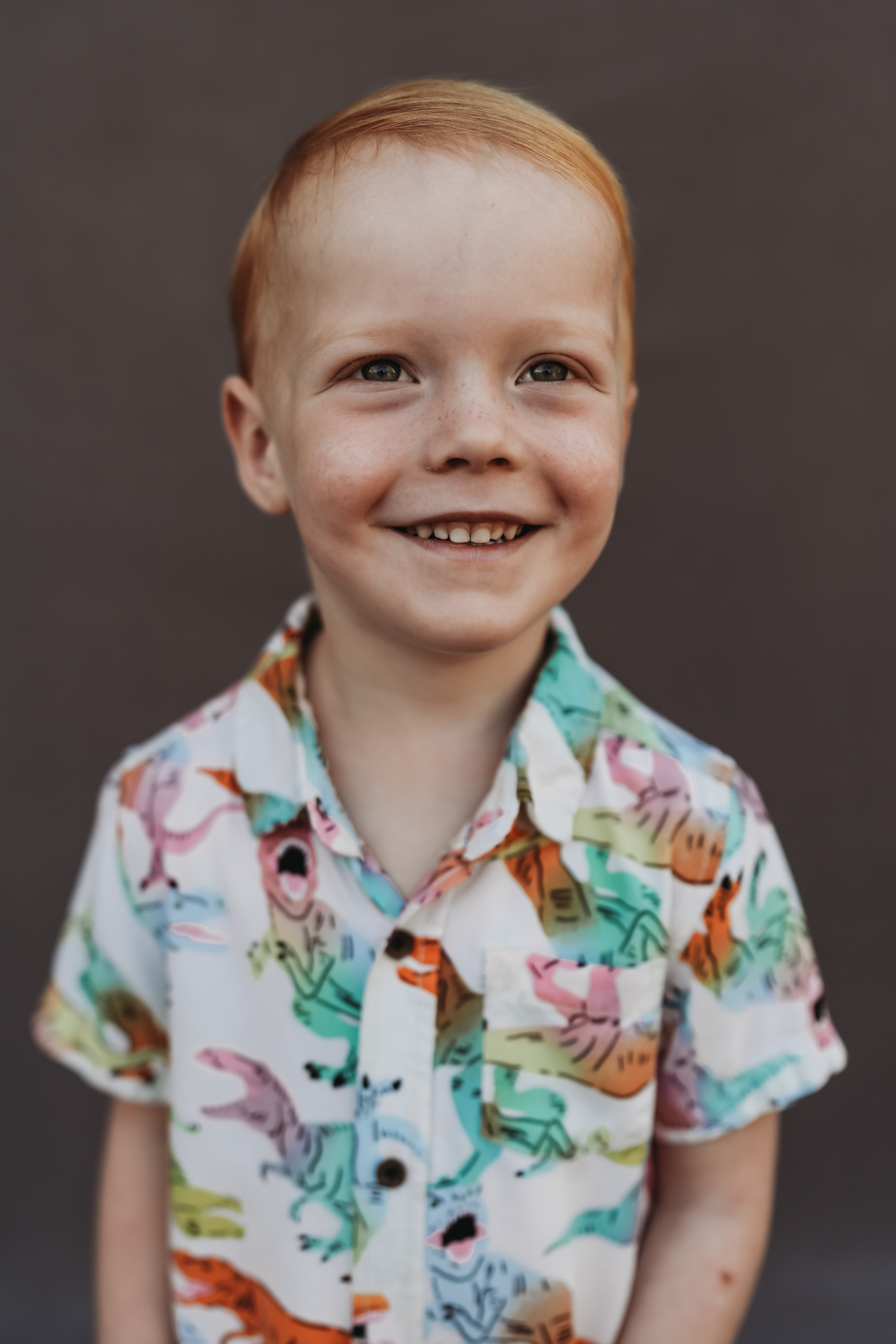 Fine art preschool portrait of a smiling boy in a colorful shirt on a dark background, Love Michelle Photography.