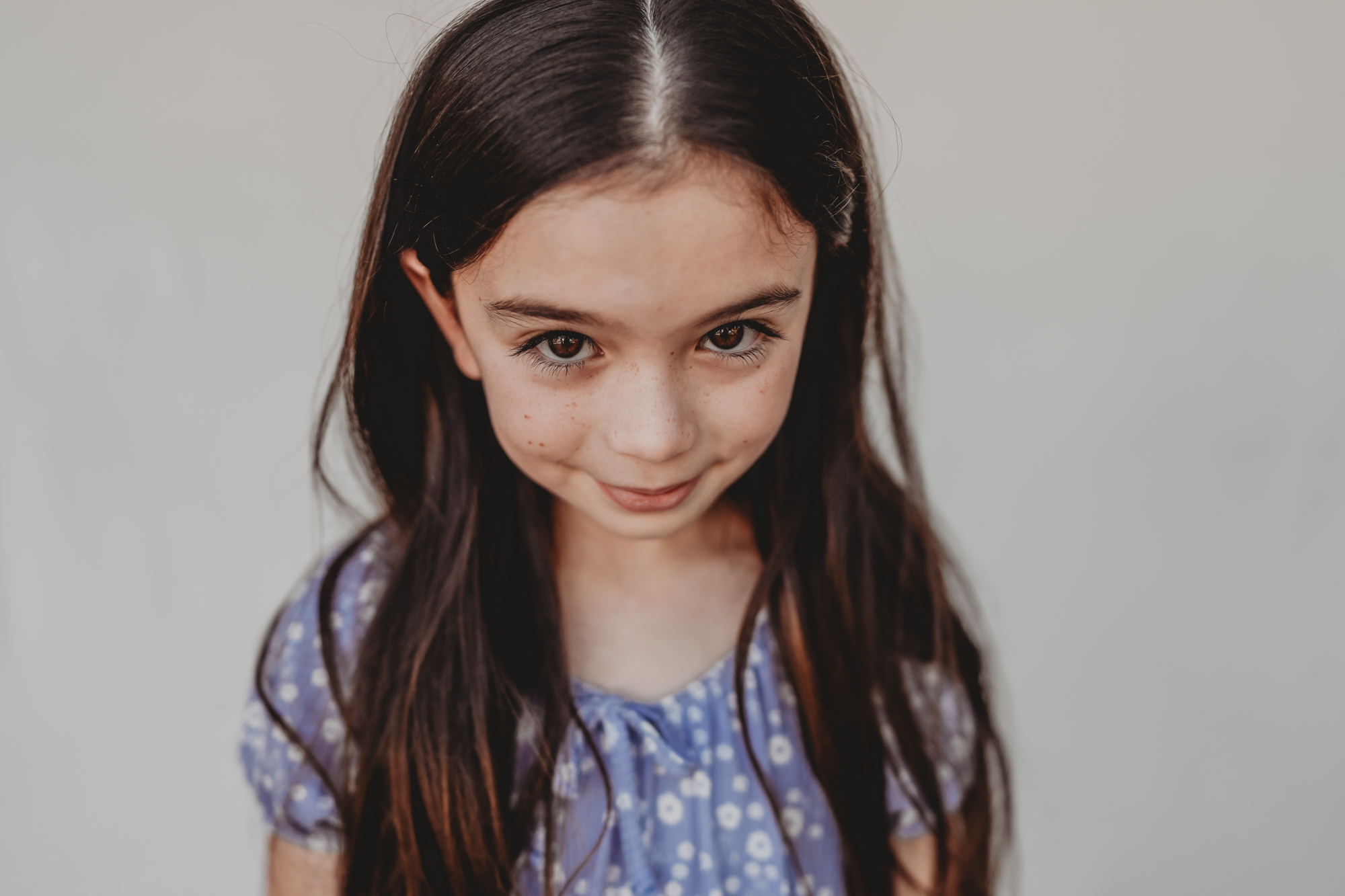 Fine art preschool portrait of a young girl with long dark hair in a blue dress, San Diego school photography.