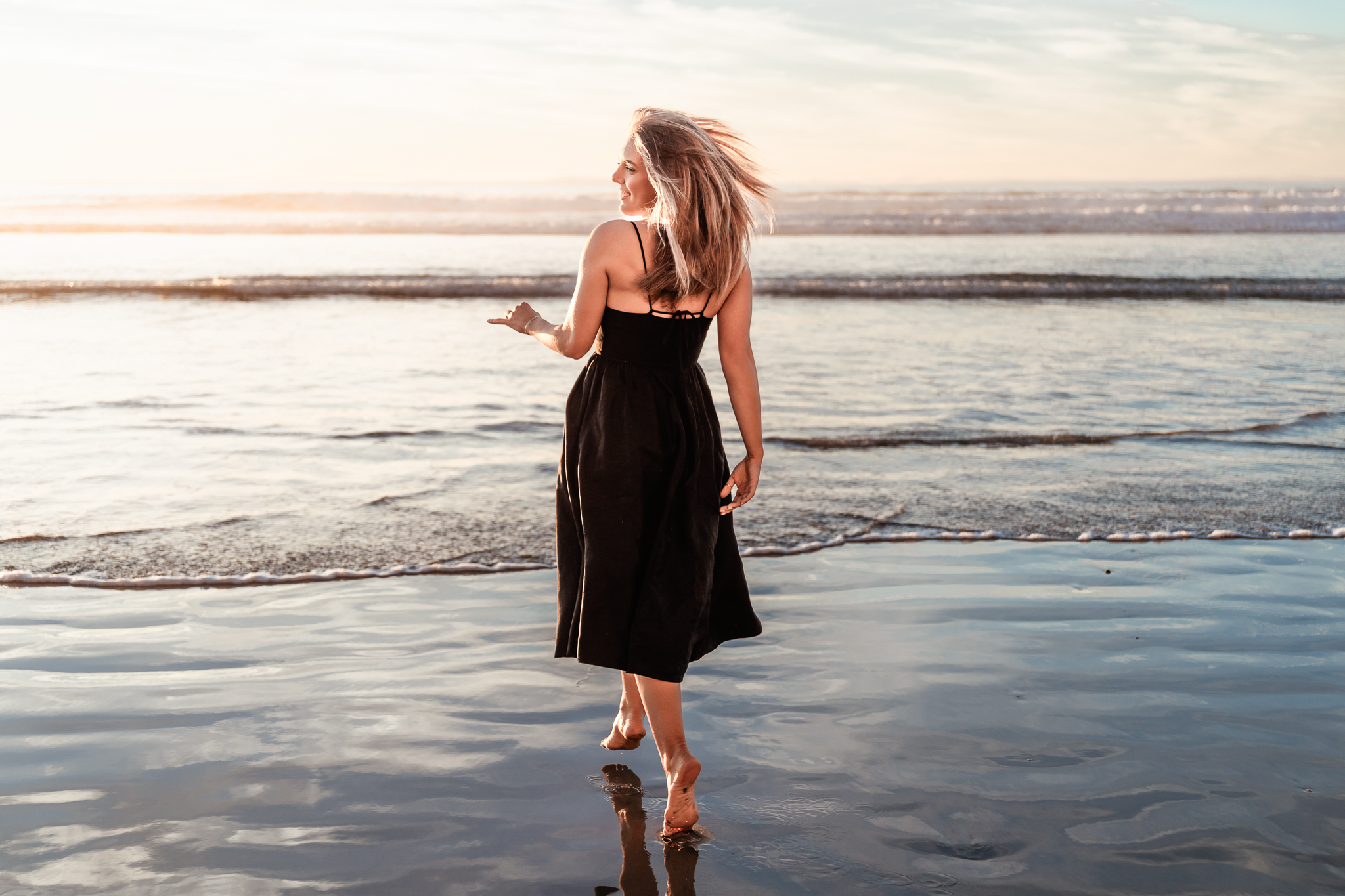 A graduating senior plays in the surf during her San Diego senior portrait session at Torrey Pines State Beach.