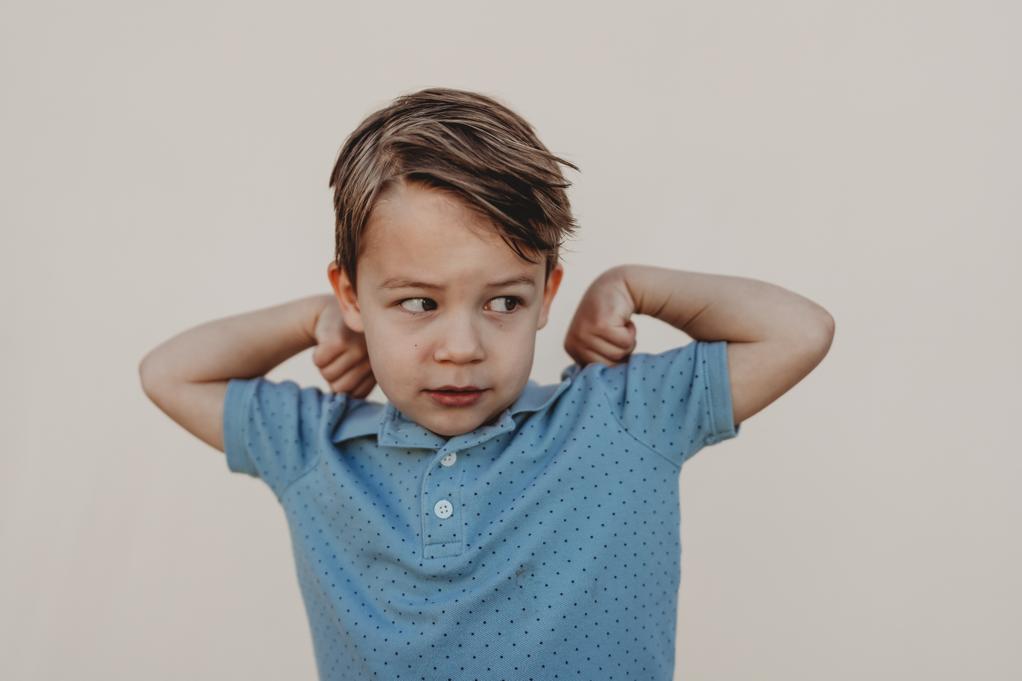 A little boy flexes for the camera during a San Diego Montessori school photos with Love Michelle Photography