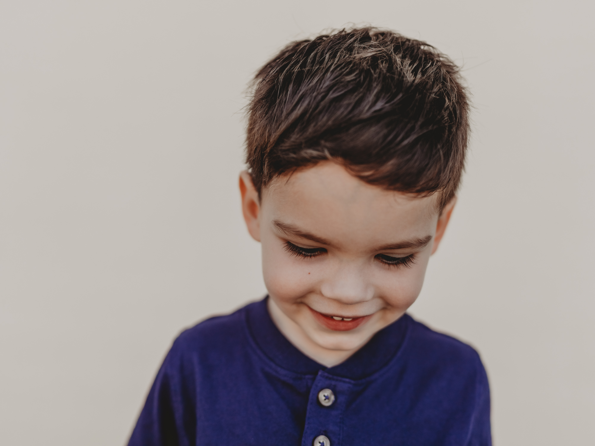 A Montessori student in San Diego poses in front of a white backdrop for his school photo by Love Michelle Photography