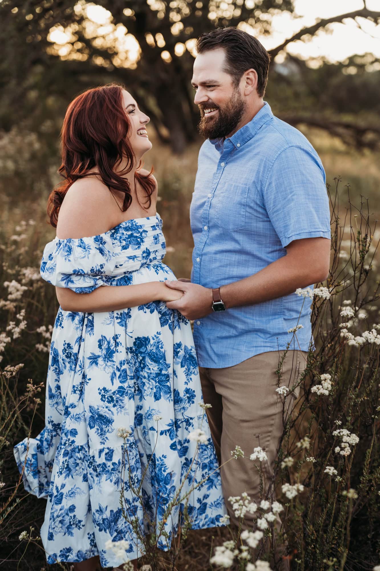 Expectant couple holding hands and smiling during natural outdoor maternity photos in San Diego