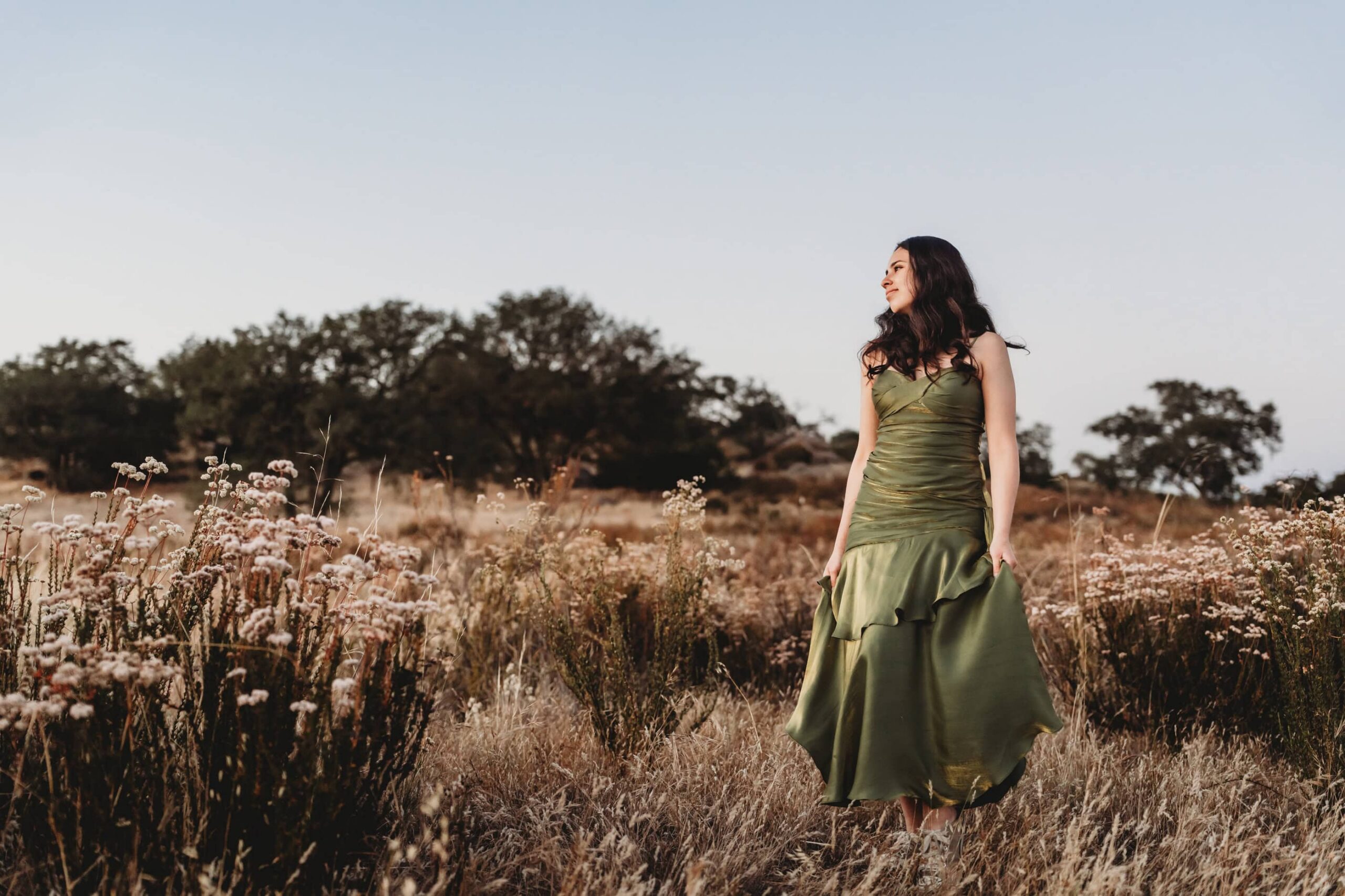 Senior girl in green dress standing in an open field, natural and candid senior portrait photography in San Diego
