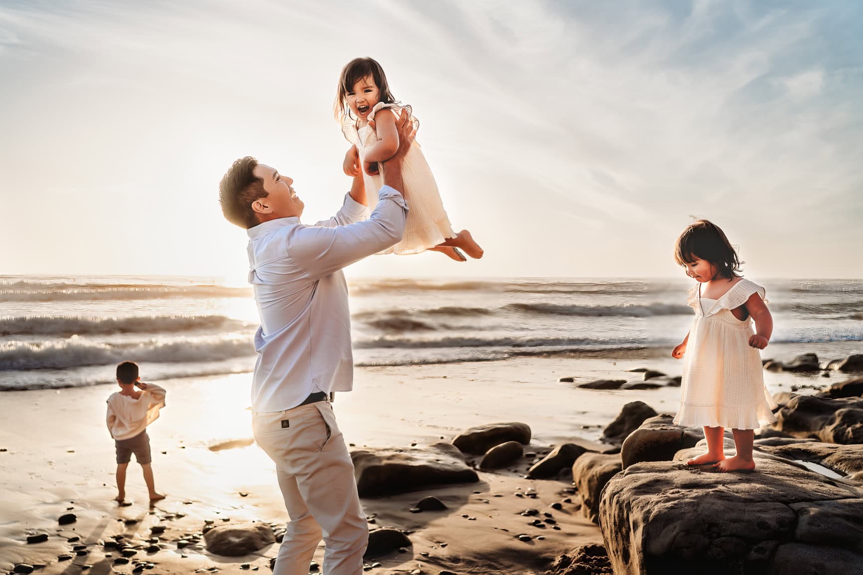 Dad reaching up to catch toddler daughter on San Diego beach family photography