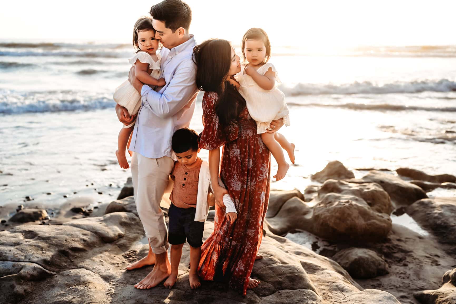 family of five with young children on rocky San Diego beach at golden hour