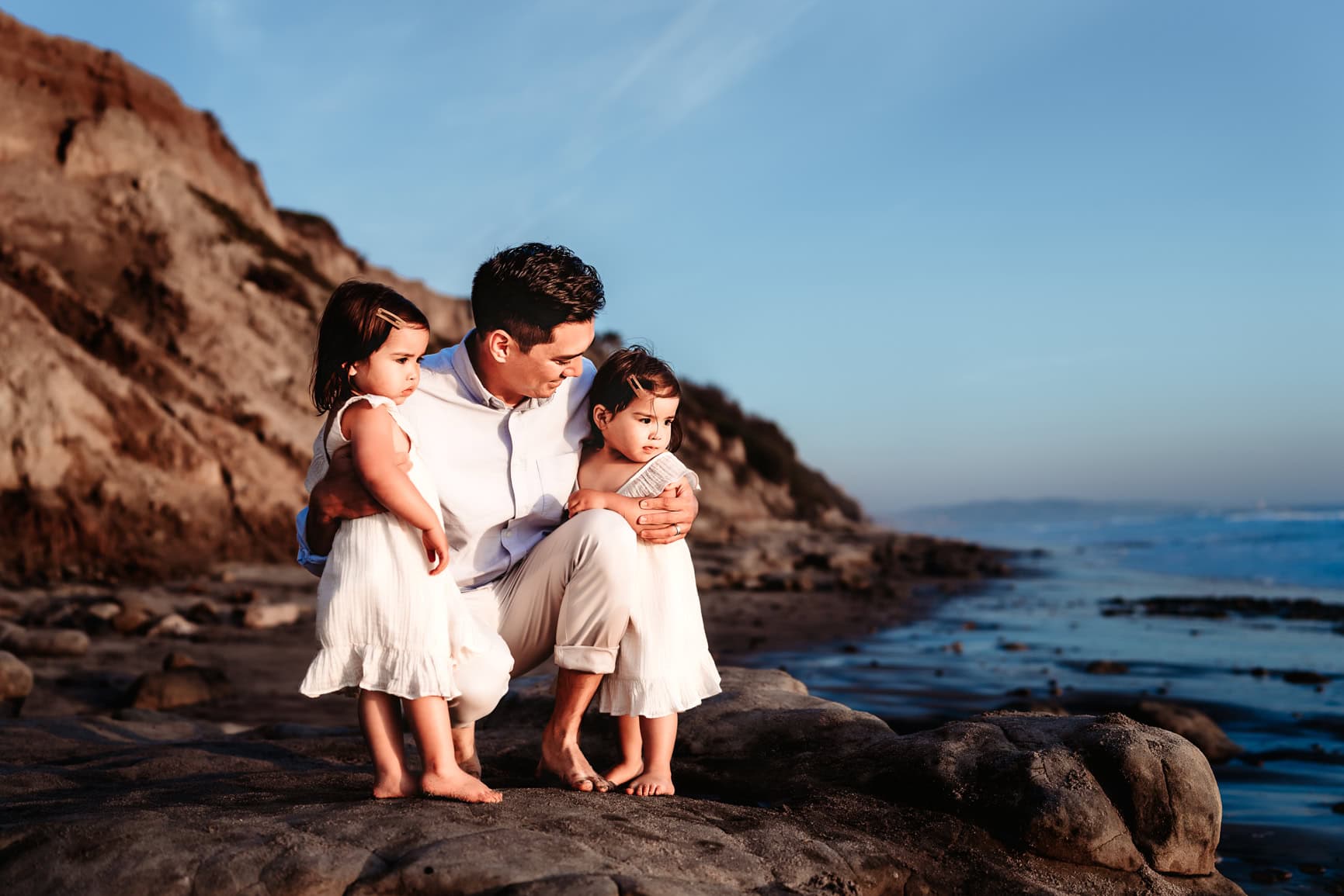Father holding young daughters on Del Mar beach during a San Diego beach family photo session